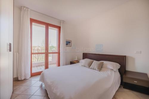 Un dormitorio con una cama blanca y una ventana. en Residence Le Ginestre Mare, en Cavallino-Treporti