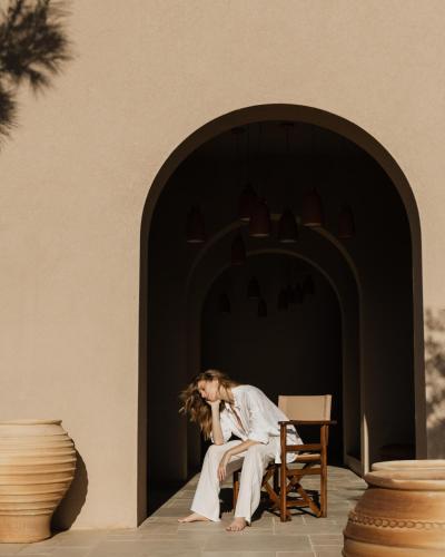 a woman sitting on a chair in front of a building at Momi Slow Living Hotel in Hersonissos