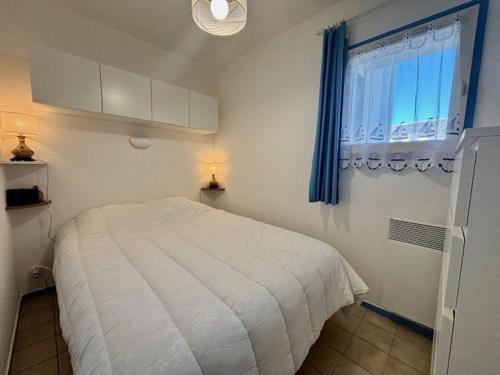une chambre avec un lit blanc et une fenêtre dans l'établissement Appartement T2 à Quiberon avec Piscine, Jardin et Animaux Acceptés - FR-1-478-308, à Quiberon