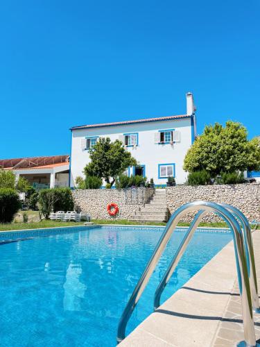 a swimming pool in front of a white house at Casa da Horta in Canha
