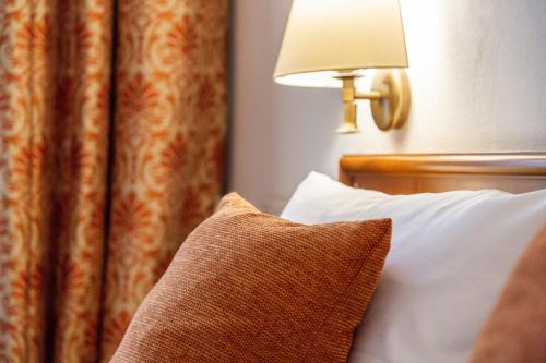 a hotel room with a bed with a pillow and a lamp at Hotel Hofgut Sternen - Ravennaschlucht in Breitnau