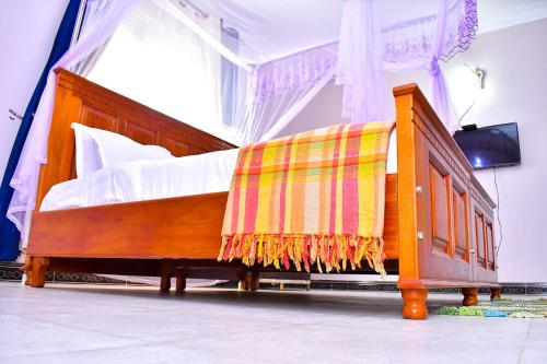 a bedroom with a wooden bed with a blanket on it at Biira Transit Residence Entebbe with free airport pickup in Entebbe