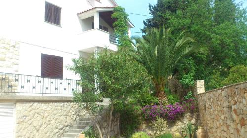 a building with a palm tree next to a stone wall at Jees Exclusive Apartments Hvar in Stari Grad