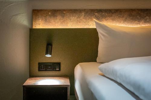 a hotel room with a bed and a nightstand with a bed sidx sidx sidx at Hotel Hofgut Sternen - Ravennaschlucht in Breitnau