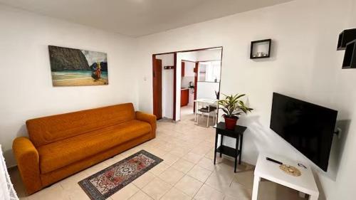 a living room with a couch and a flat screen tv at Уютная и светлая квартира с балконом рядом с ТЦ STAR in Nahariyya