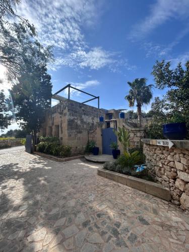 a stone building with a stone wall and trees at Ta Skorba Farmhouse Mgarr in Mġarr