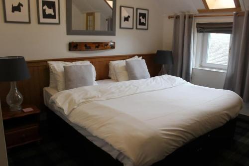 a large white bed in a bedroom with a window at Argyle Guest House in Tomintoul