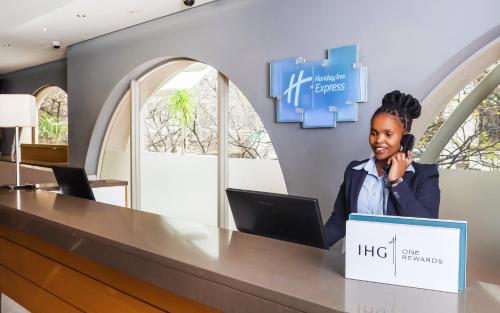 a woman talking on a phone at a desk with a laptop at Holiday Inn Express Cape Town City Centre by IHG in Cape Town
