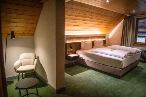 a bedroom with a bed and a chair at Hotel Hofgut Sternen - Ravennaschlucht in Breitnau