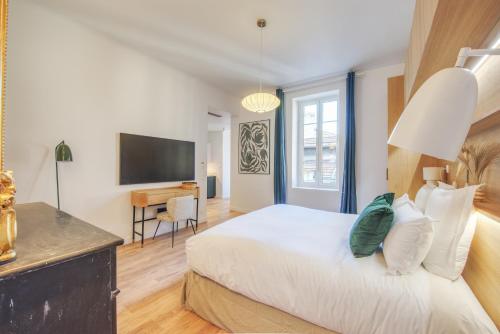 a bedroom with a large white bed and a television at Villa Victor Hugo by Odomo in Avignon