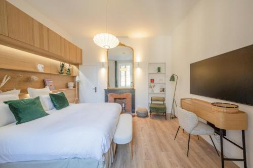 a bedroom with a bed and a desk and a television at Villa Victor Hugo by Odomo in Avignon