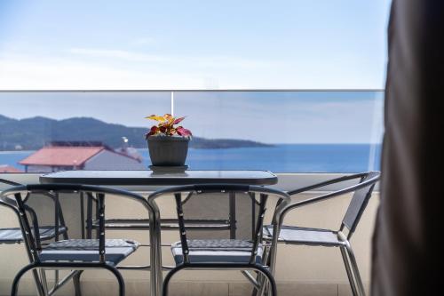 a table with two chairs and a potted plant on it at Aeli Vista Apartments in Neos Marmaras