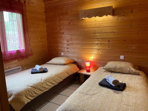 deux lits dans une cabane en rondins avec une bougie sur une table dans l'établissement Chalet de montagne à La Bresse, proche des pistes de ski et des lacs, à La Bresse
