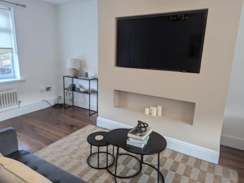 a living room with a couch and a tv on a wall at South Shields Executive Apartment in South Shields