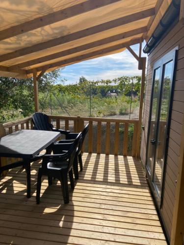 un patio avec une table et des chaises sur une terrasse dans l'établissement mobil-home 3 chambres calme et tout équipé à carry-le-rouet proche piscine avec toboggans pataugeoire et animations peu de vis à vis terrasse barbecue paddle bodyboards accès libre aux activités du camping lou soulei commerces et plage à proximité, à Carry-le-Rouet
