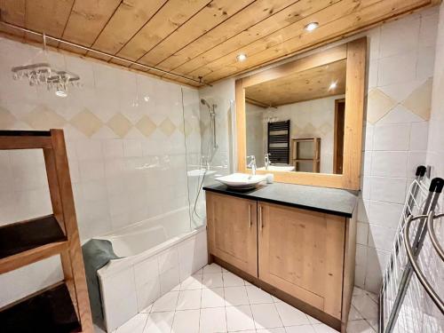 une salle de bain avec un lavabo et une baignoire dans l'établissement Appartement de charme avec terrasse, piscine et parking, proche centre et arrêt ski-bus - FR-1-624-105, à Samoëns