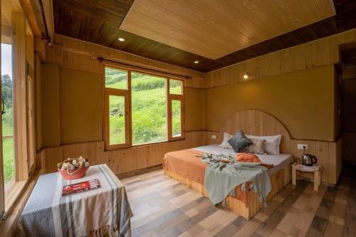 a bedroom with a bed and a table and windows at Perfect Home for Stay in Jibhi