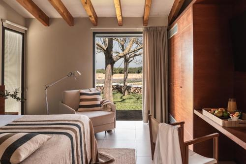 a bedroom with a bed and a chair and a window at Binissaida Boutique Hotel in Es Castell
