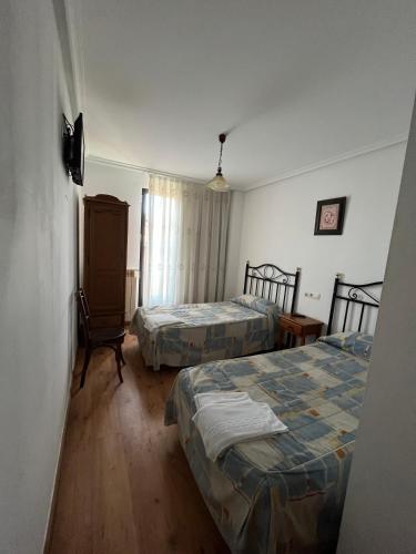 a hotel room with two beds and a chair at Hotel Rural El Puente in Mansilla de las Mulas