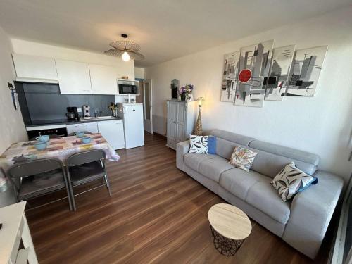 un salon avec un canapé et une table et une cuisine dans l'établissement Studio cabine à 20m de la plage avec parking privé - FR-1-224C-325, à Saint-Jean-de-Monts