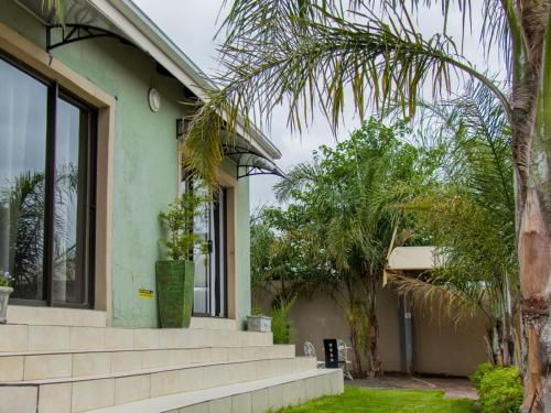 a house with a palm tree in front of it at TLMZ Guesthouse in Newcastle