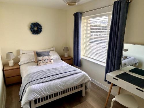a bedroom with a bed and a desk and a window at Seafront Apartment in Tramore in Tramore