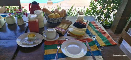 a table with plates of food and a basket of bread at Cores de Boipeba in Ilha de Boipeba