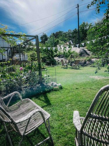 two chairs sitting in the grass in a yard at Unikt skipperhus med høner i hagen in Hvaler