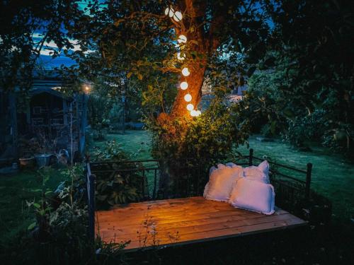a bench with pillows sitting under a tree at night at Unikt skipperhus med høner i hagen in Hvaler