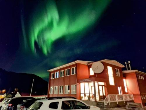 a building with the aurora in the sky behind it at The Old Post Office Guesthouse in Grundarfjordur