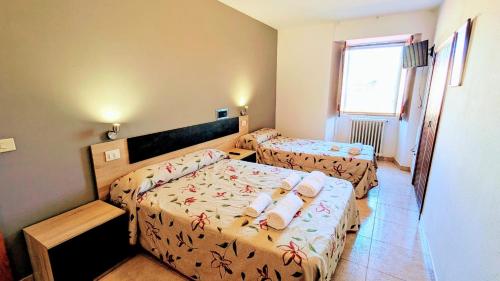 a small bedroom with two beds and a window at Restaurante y Hostal San Paio in Santiago de Compostela