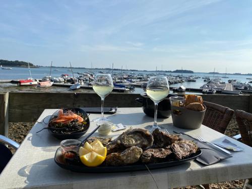 une table avec une assiette de nourriture et des verres de vin dans l'établissement Les Voiles Arradonnaises - Proche sentier côtier, à Arradon