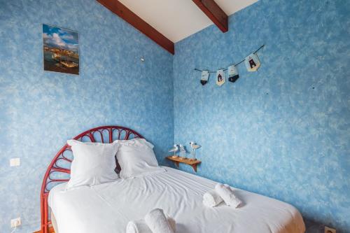 - une chambre avec des murs bleus et un lit avec des oreillers blancs dans l'établissement Maison aux Oiseaux - Welkeys, à Dolus-d'Oléron