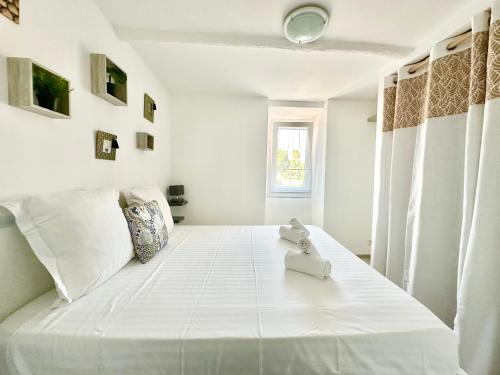 une chambre blanche avec un grand lit blanc dans l'établissement Le Bastion-Plage-vue mer, à Menton