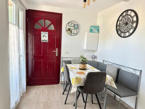 une salle à manger avec une porte rouge, une table et des chaises dans l'établissement Le Bastion-Plage-vue mer, à Menton