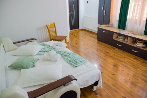 a bedroom with a white bed and a wooden floor at Casa Majestic in Călimăneşti