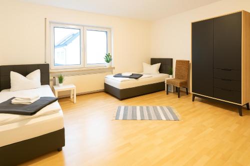 a bedroom with two beds and a cabinet and a chair at SUNNYHOME Monteurwohnungen und Apartments in Schwandorf in Schwandorf in Bayern