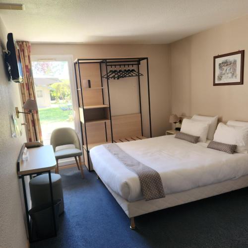 a bedroom with a bed and a chair and a window at Hôtel Nell in Saint-Marcel