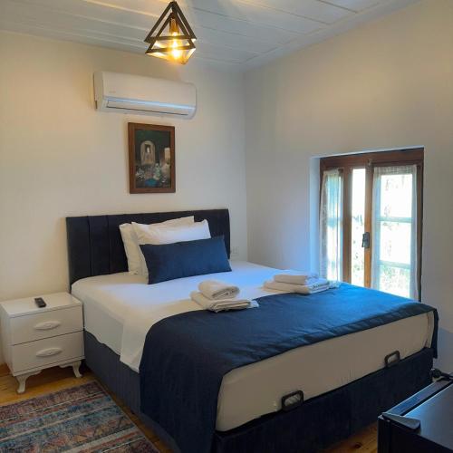 a bedroom with a large bed with blue and white sheets at Hera Pansiyon in Ayvalık