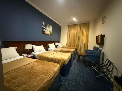 Cette chambre d'hôtel comprend 3 lits et une chaise bleue. dans l'établissement فندق نما مودة Namma Mawaddah Hotel, à La Mecque