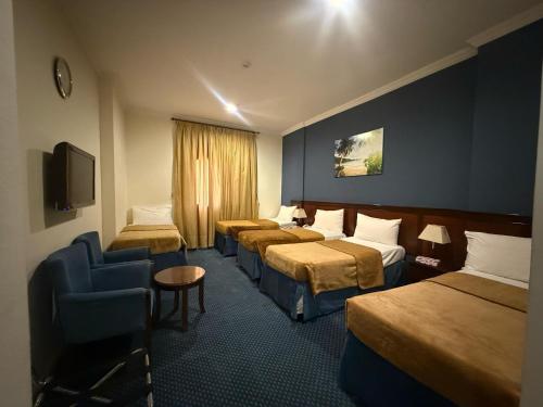 une chambre d'hôtel avec quatre lits et une chaise dans l'établissement فندق نما مودة Namma Mawaddah Hotel, à La Mecque