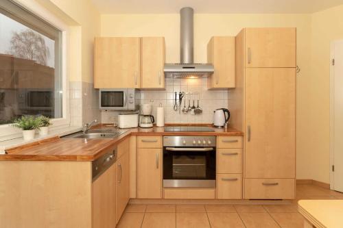 a kitchen with wooden cabinets and a stainless steel oven at Ferienwohnung Plogmann - Residenz Bernstein WHG 39 in Rerik