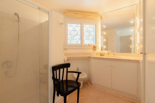 La salle de bains est pourvue d'une douche et d'une chaise noire. dans l'établissement La Maison blanche de Camargue, à Saintes-Maries-de-la-Mer