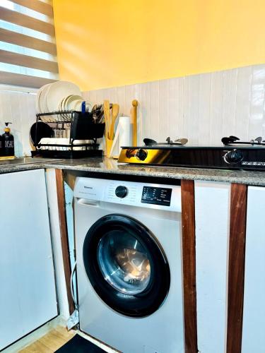 Minzi Homes في دار السلام: غسالة ملابس موضوعة تحت طاولة المطبخ