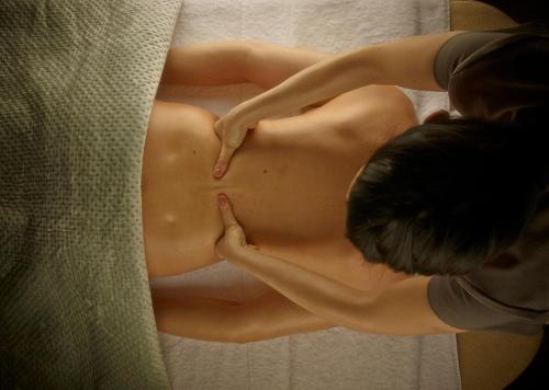 a woman sitting on a bed with her naked stomach at Dormy House Hotel in Broadway