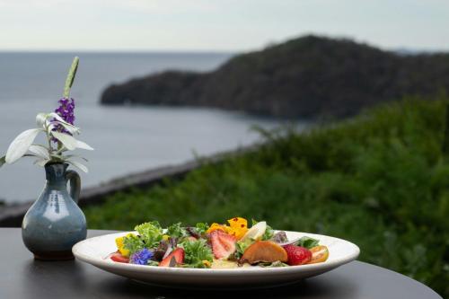a plate of food on a table next to a vase at Nekajui, a Ritz-Carlton Reserve in Papagayo, Guanacaste