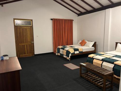 a hotel room with two beds and a door at Thomasz Lodge in Kandy