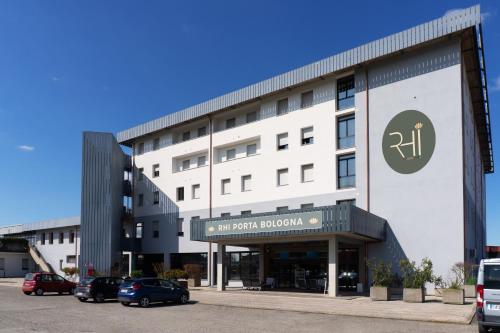 a large white building with cars parked in a parking lot at RHI Porta Bologna in Pieve di Cento
