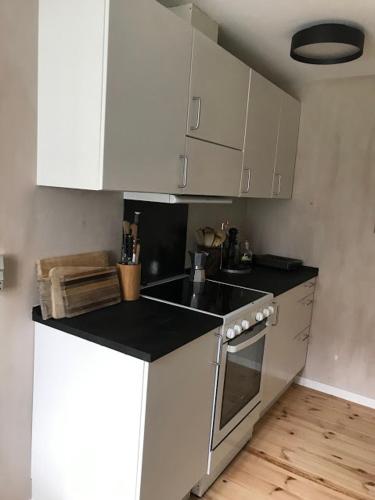 a kitchen with white cabinets and a black counter top at Byhus i Faaborg in Fåborg