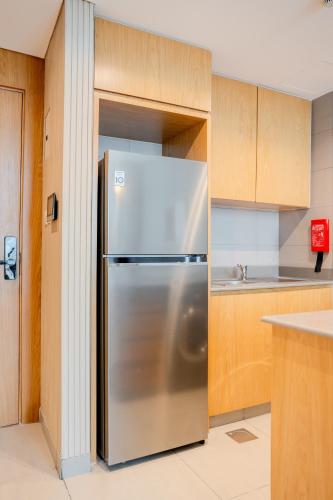 a stainless steel refrigerator in a kitchen with wooden cabinets at 1BR Private Apartment - Perfect Home in Sharjah Intl
